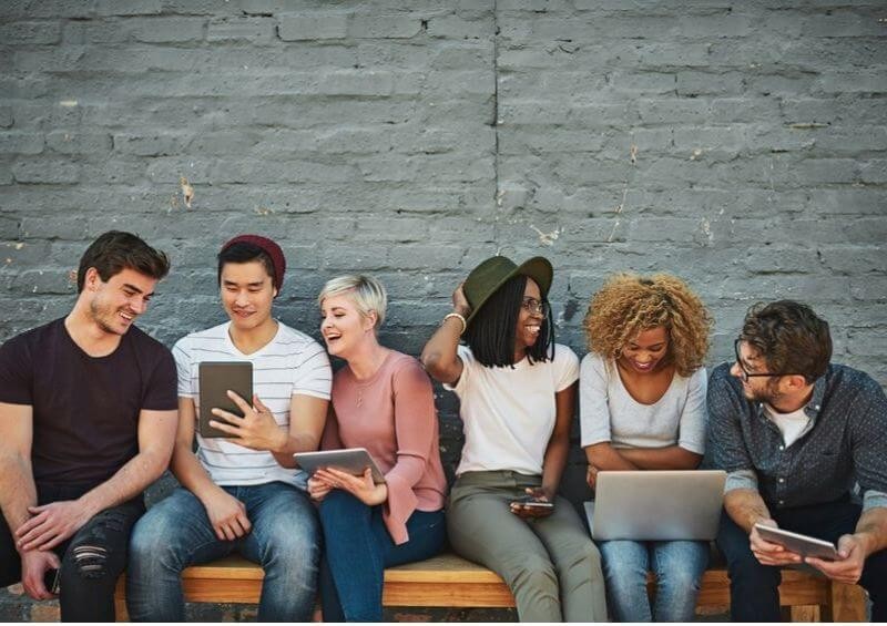 Group of millennials on their laptops and tablets laughing