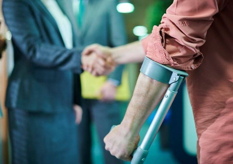 Injured man on crutches shaking employer s hand