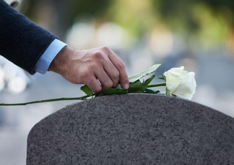 Person laying flower at a grave