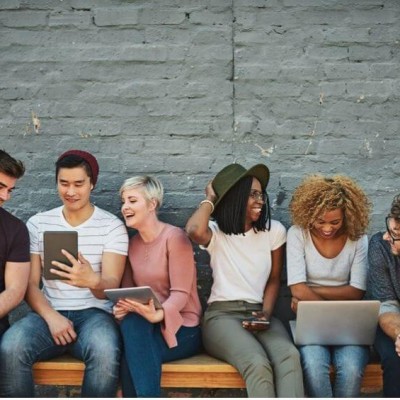 Group of millennials on their laptops and tablets laughing