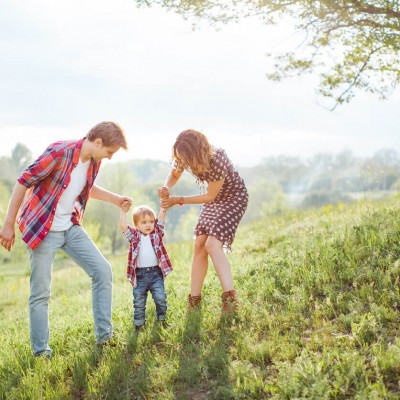 Parents and young child holding hands in the countryside
